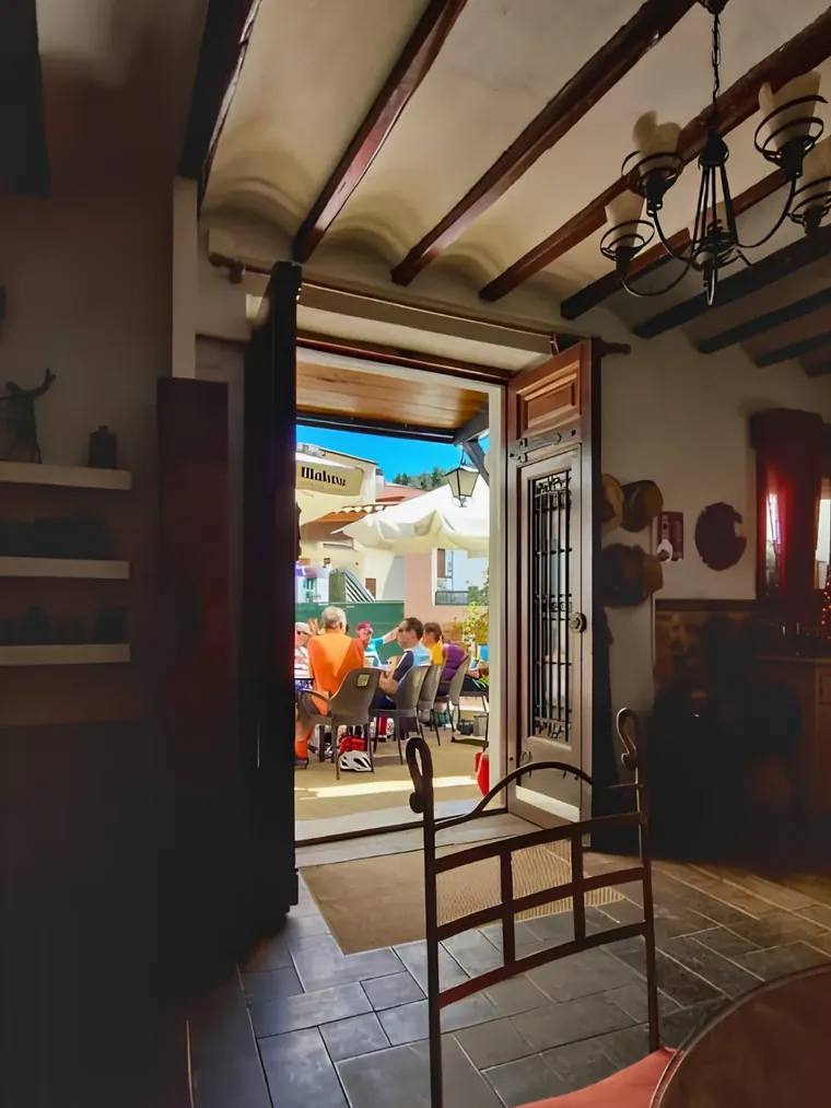 Inside the bar at Casa Blanca: beamed ceiling, chandelier, and the door open to the sunny terrace