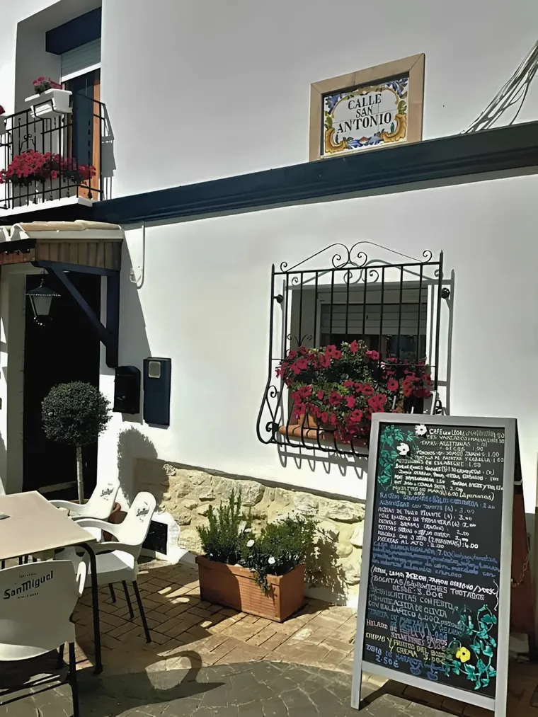 The terrace on Calle San Antonio with the day's menu on the chalkboard and geraniums in the window