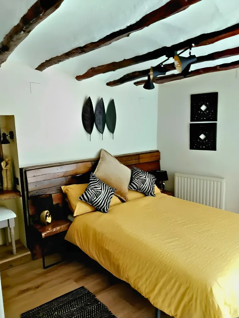 The yellow room: warm bedspread, old beams and the reclaimed-timber headboard